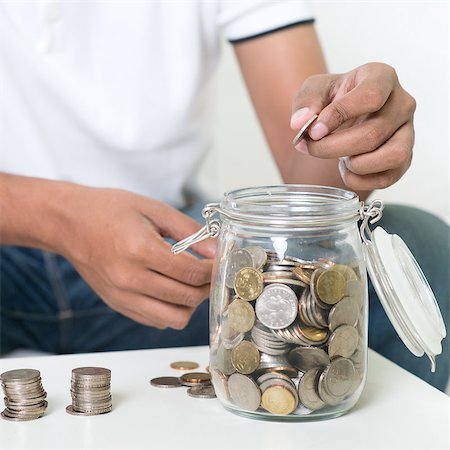 Savings concept. Focus on hand. Indian guy save money to glass jar. Stock Photo - Budget Royalty-Free & Subscription, Code: 400-08114398