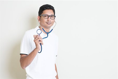 szefei (artist) - Indian medical student with stethoscope in hand. Asian man standing on plain background with shadow and copy space. Handsome male model. Stock Photo - Budget Royalty-Free & Subscription, Code: 400-08116559