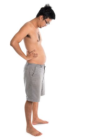 Full length Asian man looking at his fat belly, standing isolated on white background. Stock Photo - Budget Royalty-Free & Subscription, Code: 400-08112838