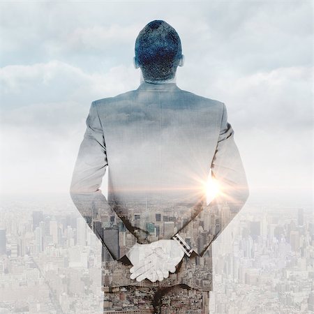 Young businessman standing with hands behind back against clouds over city Stock Photo - Budget Royalty-Free & Subscription, Code: 400-08136886