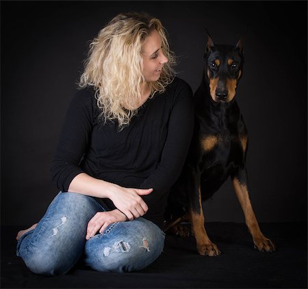 pinscher - woman sitting beside doberman pinscher on black background Photographie de stock - Aubaine LD & Abonnement, Code: 400-08187939