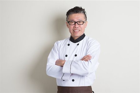 Portrait of confident 50s mature Asian male chef in uniform arms crossed, standing on plain background with shadow, copy space. Stock Photo - Budget Royalty-Free & Subscription, Code: 400-08225155