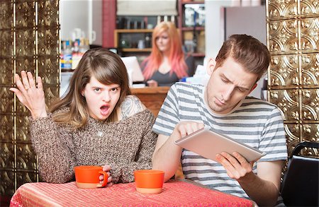 Insulted woman at table with young man using tablet Stock Photo - Budget Royalty-Free & Subscription, Code: 400-08253175