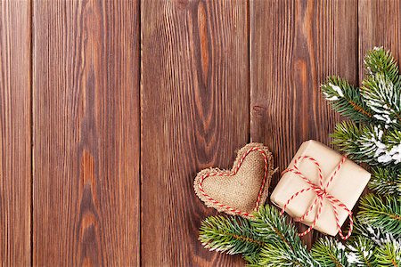 Christmas tree branch with snow, gift box and heart toy on wooden table. View with copy space Stock Photo - Budget Royalty-Free & Subscription, Code: 400-08295839