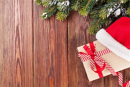 Christmas tree branch and santa hat with gift box on wooden table. Top view with copy space Stock Photo - Budget Royalty-Free & Subscription, Code: 400-08299714