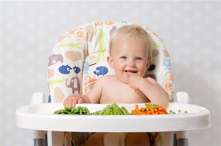 Baby girl sitting in a highchair eating raw, seasonal vegetables: carrots, beans, peas, celery Stock Photo - Budget Royalty-Free & Subscription, Code: 400-08332495