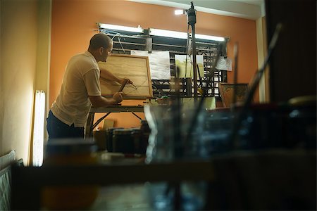 simsearch:400-07899762,k - Adult man at work as artist, chiselling a bas-relief in his atelier. He works with hammer and ceasel on a wood painting. Stock Photo - Budget Royalty-Free & Subscription, Code: 400-08348830