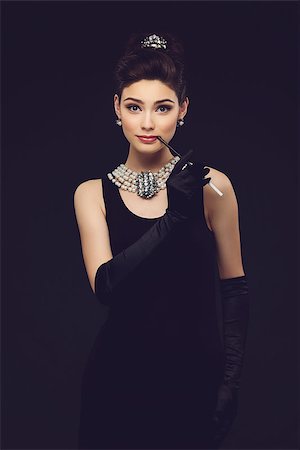 Beautiful woman looking like Audrey Hepburn standing with cigarette-holder Stock Photo - Budget Royalty-Free & Subscription, Code: 400-08403512