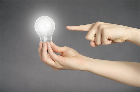 simsearch:400-04265413,k - A finger pointing to a glowing light bulb in a hand Stock Photo - Budget Royalty-Free & Subscription, Code: 400-08410746