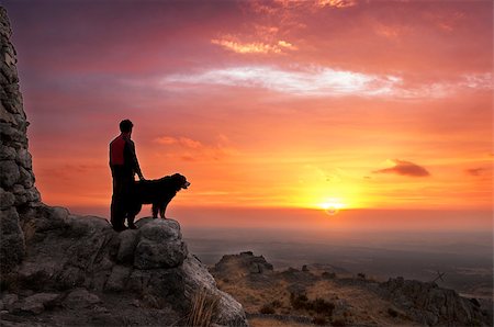 silhouette of man standing in a mountain top - Man and his faithful companion watching the sunrise on top of the mountain Stock Photo - Budget Royalty-Free & Subscription, Code: 400-08426799
