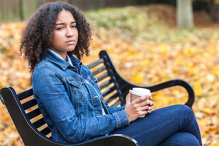 sad african children - Beautiful mixed race African American girl teenager female young woman drinking takeaway coffee outside sitting on a park bench in autumn or fall looking sad depressed or thoughtful Stock Photo - Budget Royalty-Free & Subscription, Code: 400-08430035
