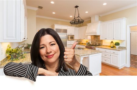 Hispanic Woman with Thumbs Up In Custom Kitchen Interior Leaning on White. Stock Photo - Budget Royalty-Free & Subscription, Code: 400-08431533