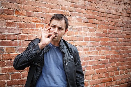 simsearch:400-05207678,k - Man smoker in the background of an old brick wall. Bully in the alley. Smoking bad boy. Stock Photo - Budget Royalty-Free & Subscription, Code: 400-08498353