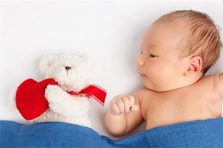 Cute newborn baby lying with a teddy bear on bed under a blanket Stock Photo - Budget Royalty-Free & Subscription, Code: 400-08668739