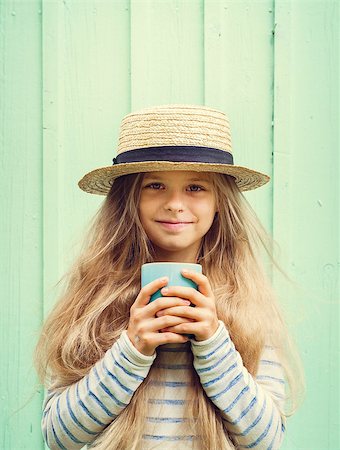 sensitive - Cute little girl stands near a turquoise wall in boater hat and holding cup. Space for text.Negative speace Stock Photo - Budget Royalty-Free & Subscription, Code: 400-08706043