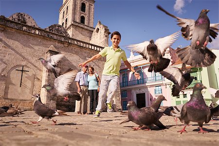 Happy tourist on holidays during vacation trip. Hispanic people traveling in Havana, Cuba. Grandpa and grandson feeding birds, with child running chasing pigeons Stock Photo - Budget Royalty-Free & Subscription, Code: 400-08706428