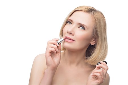 Beautiful middle aged woman with smooth skin and short blond hair applying lipstick. Beauty shot. Isolated over white background. Copy space. Photographie de stock - Aubaine LD & Abonnement, Code: 400-08730750