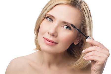 Beautiful middle aged woman with smooth skin and short blond hair applying fix gel to eyebrows. Beauty shot. Isolated over white background. Copy space. Photographie de stock - Aubaine LD & Abonnement, Code: 400-08730751