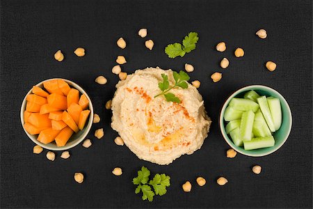 simsearch:400-06864386,k - Delicious hummus background. Hummus, chickpeas, fresh carrot and cucumber vegetable on black background, top view. Traditional eastern cuisine. Stock Photo - Budget Royalty-Free & Subscription, Code: 400-08732189