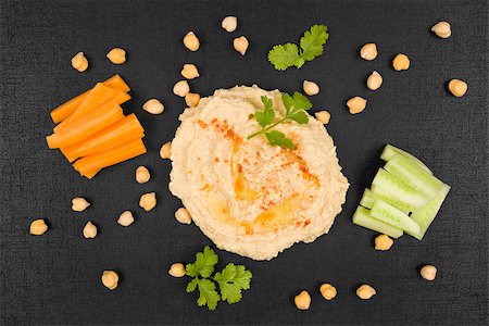 simsearch:400-06864386,k - Delicious hummus background. Hummus, chickpeas, fresh carrot and cucumber vegetable on black background, top view. Traditional eastern cuisine. Stock Photo - Budget Royalty-Free & Subscription, Code: 400-08732190