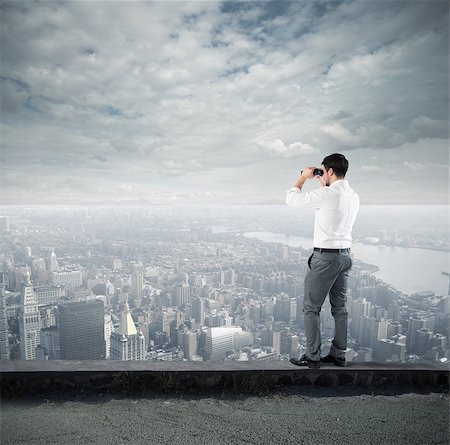 Businessman looks at the city from the roof with binoculars Stock Photo - Budget Royalty-Free & Subscription, Code: 400-08733516