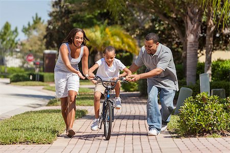 A young African American family with boy child riding his bicycle and his happy excited parents giving encouragement next to him Stock Photo - Budget Royalty-Free & Subscription, Code: 400-08775622