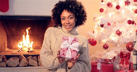 sweater and fireplace - Close up of beautiful black woman holding present while seated by fireplace Stock Photo - Budget Royalty-Free & Subscription, Code: 400-08811125