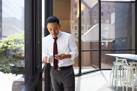 Asian businessman standing in modern office using phone Stock Photo - Budget Royalty-Free & Subscription, Code: 400-08838794