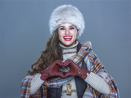 Winter things. Portrait of smiling modern woman in fur hat isolated on cold blue showing heart shaped hands Stock Photo - Budget Royalty-Free & Subscription, Code: 400-08864107