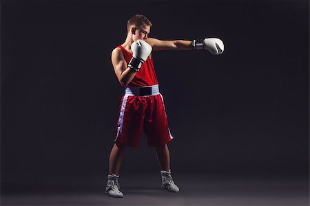 Young handsome boxer sportsman in red boxer suit and white gloves standing on black backgound. Copy space. Stock Photo - Budget Royalty-Free & Subscription, Code: 400-08861354