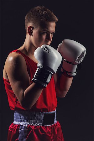 Young handsome boxer sportsman in red boxer suit and white gloves standing on black backgound. Copy space. Stock Photo - Budget Royalty-Free & Subscription, Code: 400-08861359