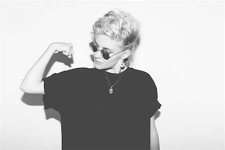 Stylish fashion sexy blonde bad girl in a black t-shirt and rock sunglasses. Dangerous rocky emotional woman. Black and white toned. White background, not isolated Stock Photo - Budget Royalty-Free & Subscription, Code: 400-08862441