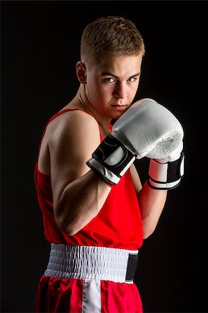 Young handsome boxer sportsman in red boxer suit and white gloves standing on black backgound. Copy space. Stock Photo - Budget Royalty-Free & Subscription, Code: 400-08888257