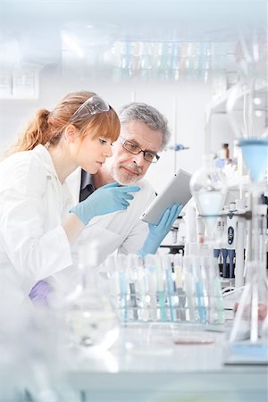 simsearch:400-09011632,k - Health care researchers working in life scientific laboratory. Young female research scientist and senior male supervisor looking focused at tablet computer screen evaluating and analyzing study data. Stock Photo - Budget Royalty-Free & Subscription, Code: 400-09010456