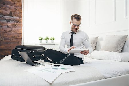 Young businessman on bed working with a tablet laptop from his hotel room Stock Photo - Budget Royalty-Free & Subscription, Code: 400-09062853