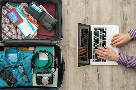 Traveler getting ready to leave and packing his bag, he is typing on a laptop anp planning his trip Stock Photo - Budget Royalty-Free & Subscription, Code: 400-09082291