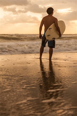 silhouettes surfboards in the sand - Rear view of young man male surfer with white surfboard looking at surf on a beach at sunset or sunrise Stock Photo - Budget Royalty-Free & Subscription, Code: 400-09140485