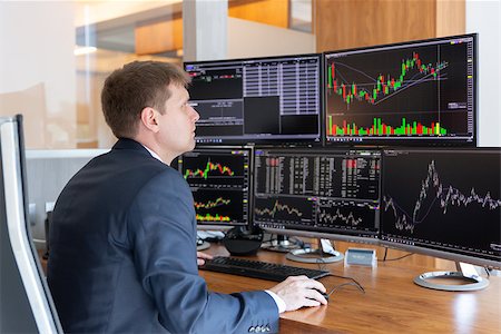 Businessman trading stocks. Stock traders looking at graphs, indexes, numbers and analyses on multiple computer screens in modern trading office. Stock Photo - Budget Royalty-Free & Subscription, Code: 400-09170886