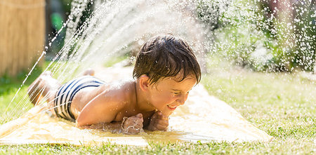 Boy cooling down with garden hose, family in the background on a hot summer day Stock Photo - Budget Royalty-Free & Subscription, Code: 400-09224929