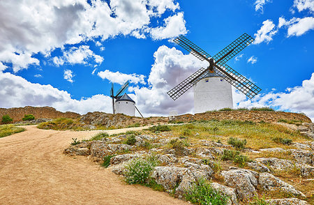 Wind mills at knolls at Consuegra, Toledo region, Castilla La Mancha, Spain. Route of Don Quixote with windmills. Summer landscape with blue sky and clouds. Fotografie stock - Microstock e Abbonamento, Codice: 400-09238230