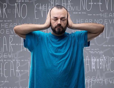 Front view portrait of a calm man with closed eyes covering his ears with his hands against conceptual background with written advice to hear no evil Stock Photo - Budget Royalty-Free & Subscription, Code: 400-09273378