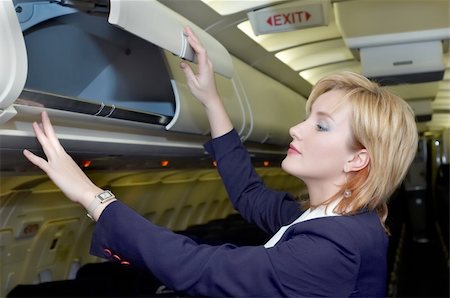 servicing a plane - Air hostess is checking open luggage box in the cabin Stock Photo - Budget Royalty-Free & Subscription, Code: 400-03918311