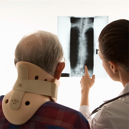 Over the shoulders view of mid-adult Caucasian female pointing at an x-ray as elderly Caucasian male in neck brace looks on. Stock Photo - Budget Royalty-Free & Subscription, Code: 400-03924225