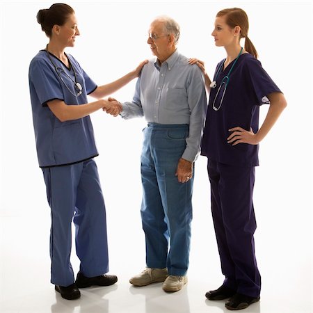 Mid-adult Caucasian female in scrubs shaking hand of elderly Caucasian male with another mid-adult Caucasian female with hand on his shoulder. Stock Photo - Budget Royalty-Free & Subscription, Code: 400-03924241