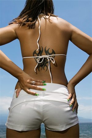 Rear view of multi ethnic young adult woman on beach with hands on hips and tattoo. Stock Photo - Budget Royalty-Free & Subscription, Code: 400-03924890