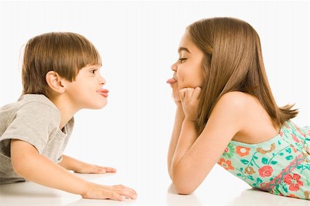 Portrait of girl and boy lying looking at eachother sticking out tongues. Stock Photo - Budget Royalty-Free & Subscription, Code: 400-03926426