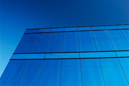 simsearch:614-06624685,k - A modern office block with a glass facade reflects the clear blue of a cloudless sky, with some power lines. Fotografie stock - Microstock e Abbonamento, Codice: 400-03921085