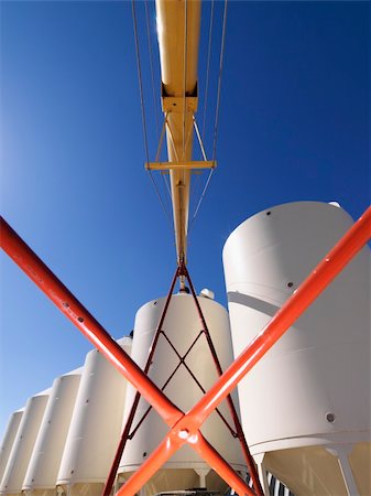 Low angle view of metal grain storage silo facility against blue background. Stockbilder - Microstock & Abonnement, Bildnummer: 400-03937828