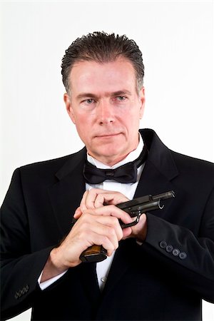 simsearch:700-00546343,k - Man in formal attire, cocking a 9mm automatic weapon, taken in front a white background. Stock Photo - Budget Royalty-Free & Subscription, Code: 400-03937912