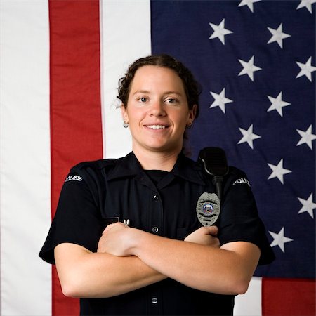 female police officer happy - Portrait of mid adult Caucasian policewoman standing with arms crossed with American flag as backdrop smiling at viewer. Photographie de stock - Aubaine LD & Abonnement, Code: 400-03940754